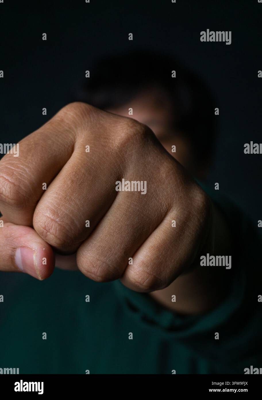 Eine Nahaufnahme zeigt eine geballte Faust, die direkt auf das Kameralens zuschlägt und einen kraftvollen und dynamischen visuellen Effekt erzeugt. Ein erwachsener asiatischer Mann Stockfoto