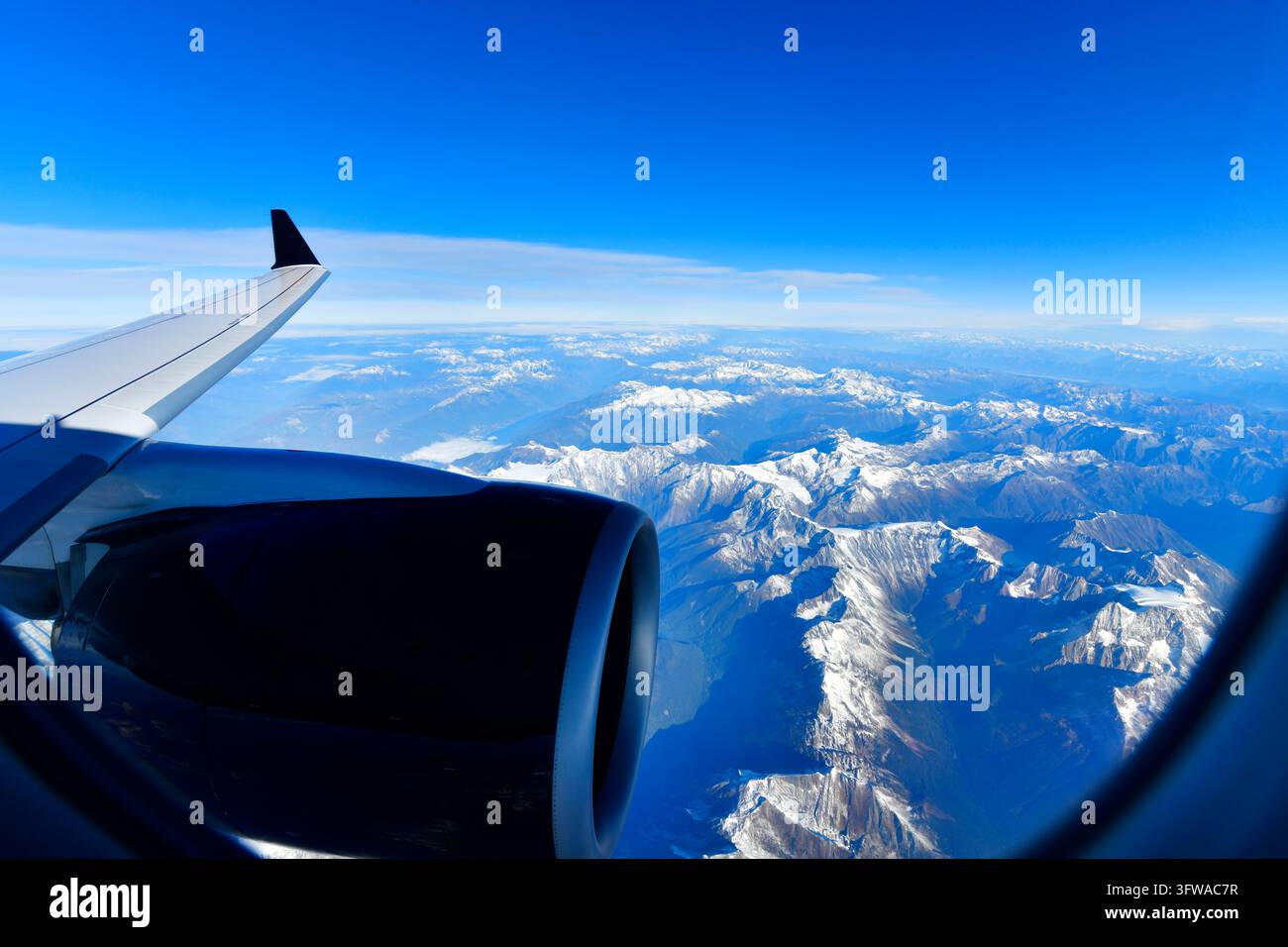 Scenische Luftaufnahme aus dem Flugzeugfenster, das hoch über den schneebedeckten Rocky Mountains in Kanada unter einem strahlend blauen Himmel fliegt. Stockfoto