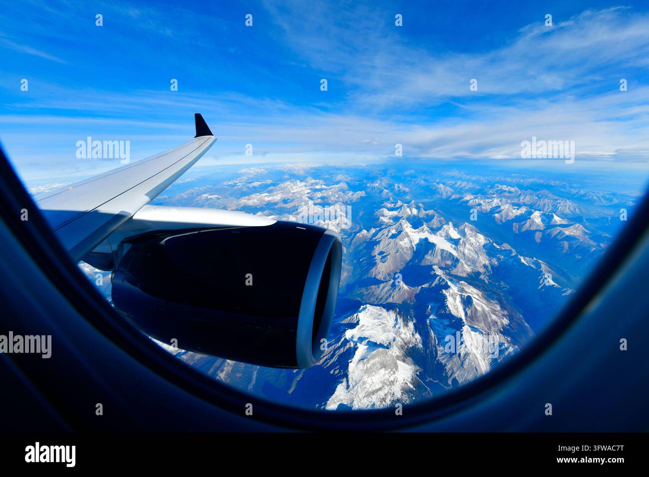 Scenische Luftaufnahme aus dem Flugzeugfenster, das hoch über den schneebedeckten Rocky Mountains in Kanada unter einem strahlend blauen Himmel fliegt. Stockfoto