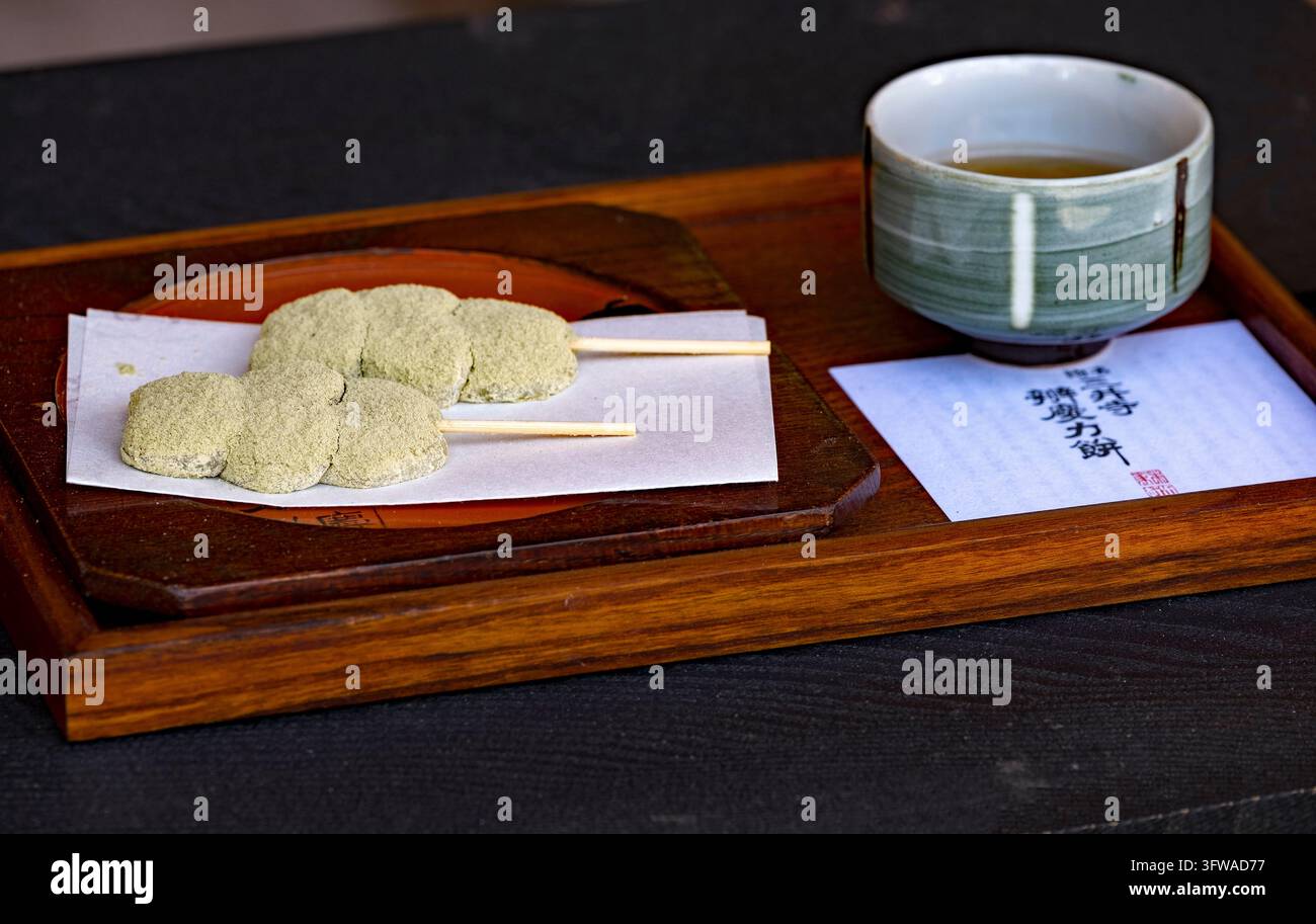 Japanischer Tee, serviert in einer Porzellantasse, begleitet von „Okashi“-Spießen mit einem traditionellen süßen Reisgebäck namens „Mochi“ oder „Dango-Mochi“, Japan Stockfoto