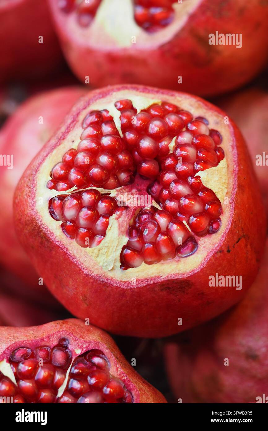 Geschnittene Granatäpfel zeigen Büschel von Samen an einem Marktstand Stockfoto