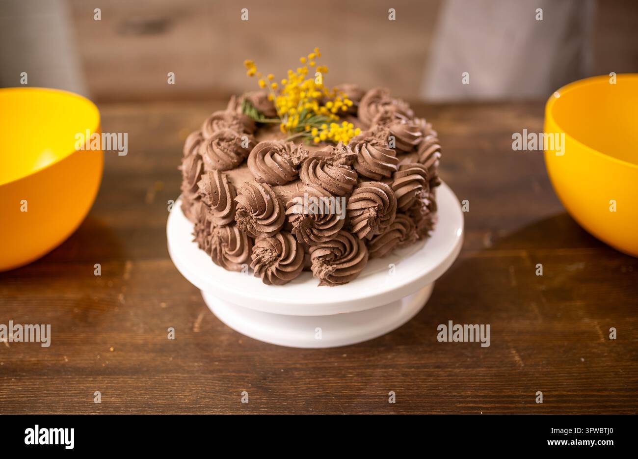 Schokoladencremetorte verziert mit Herz-Toppern und gepippten Rosetten auf dem Tortenständer Stockfoto