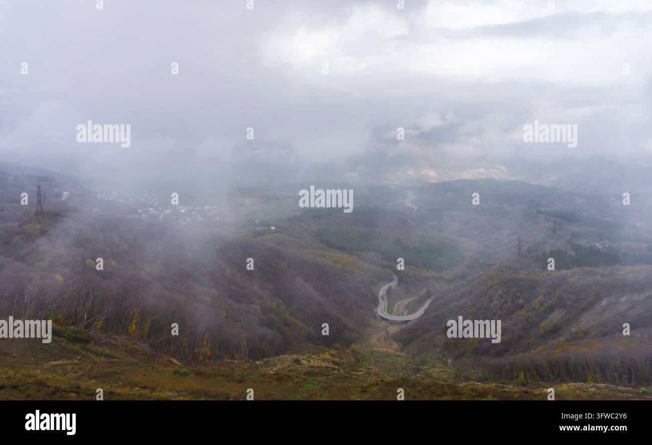 Oberblick auf die Kurve der Straße im Canyon, Dörfer in Wolken und Nebel. Berge in Wolken und Nebel verborgen Stockfoto