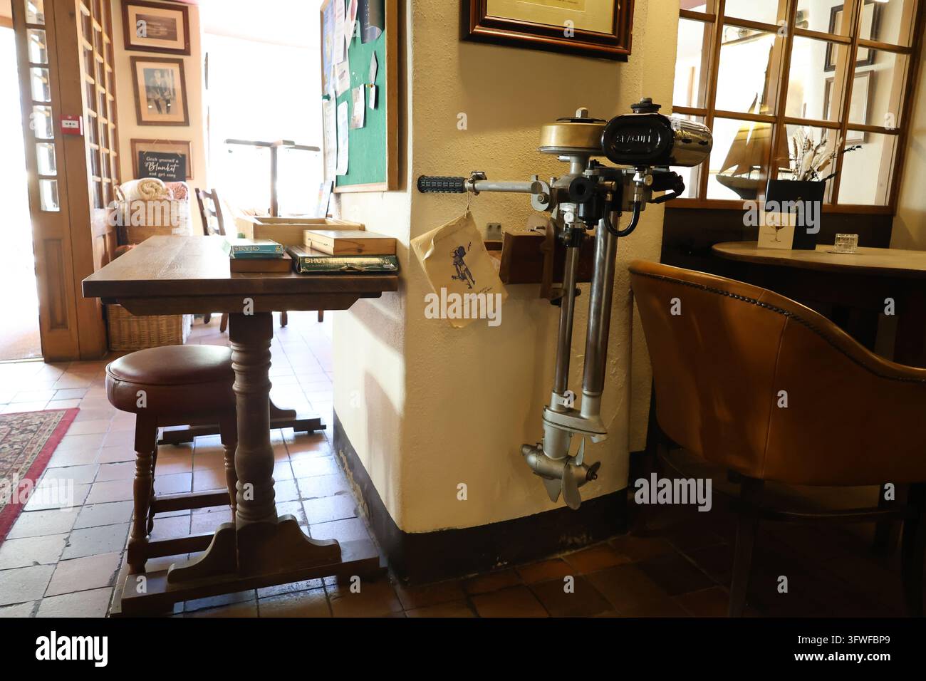 Traditionelles Pub-Interieur in Noss Mayo mit einem vintage Außenbordmotor an der Wand, Holzstühlen und gerahmten Bildern. Stockfoto