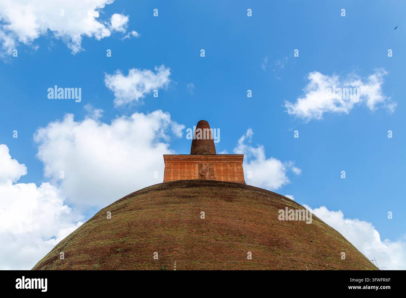 Spitze eines riesigen alten Ziegelstupas vor blauem Himmel und weißen Wolken, Nord-Zentral-Provinz, Anuradhapura, Sri Lanka Stockfoto
