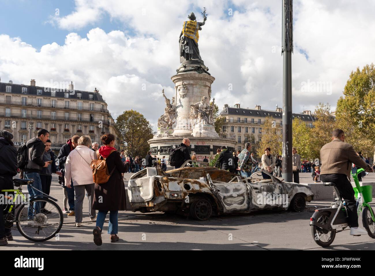 Menschen betrachten und fotografieren ein ausgebranntes Auto auf dem Place de la République. Die Nachwirkungen einer Demonstration in Paris am Vortag Stockfoto