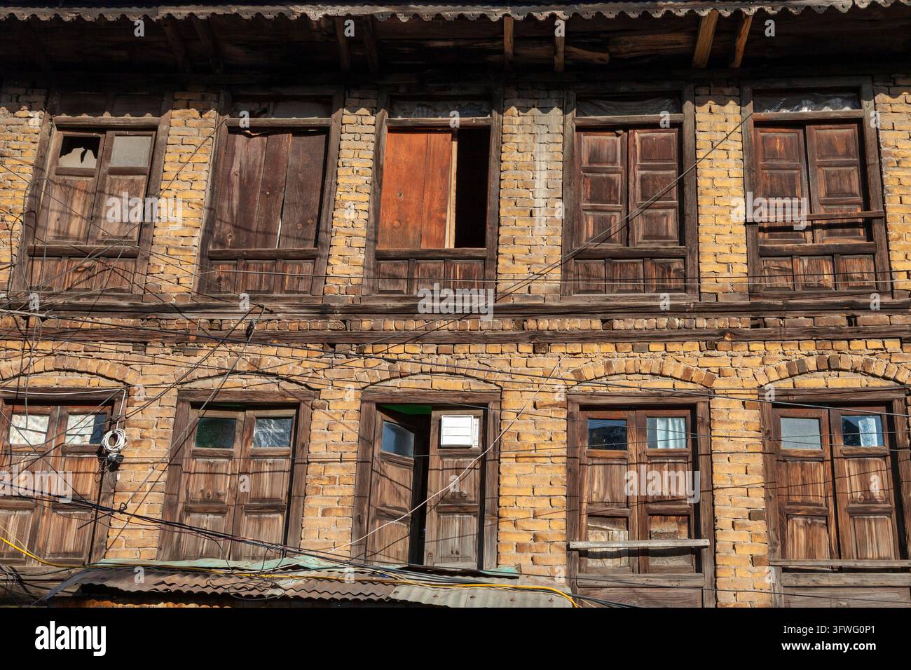 Fassade eines alten gelben Backsteinhauses mit Holzläden, Jammu und Kashmir, Srinagar, Indien Stockfoto