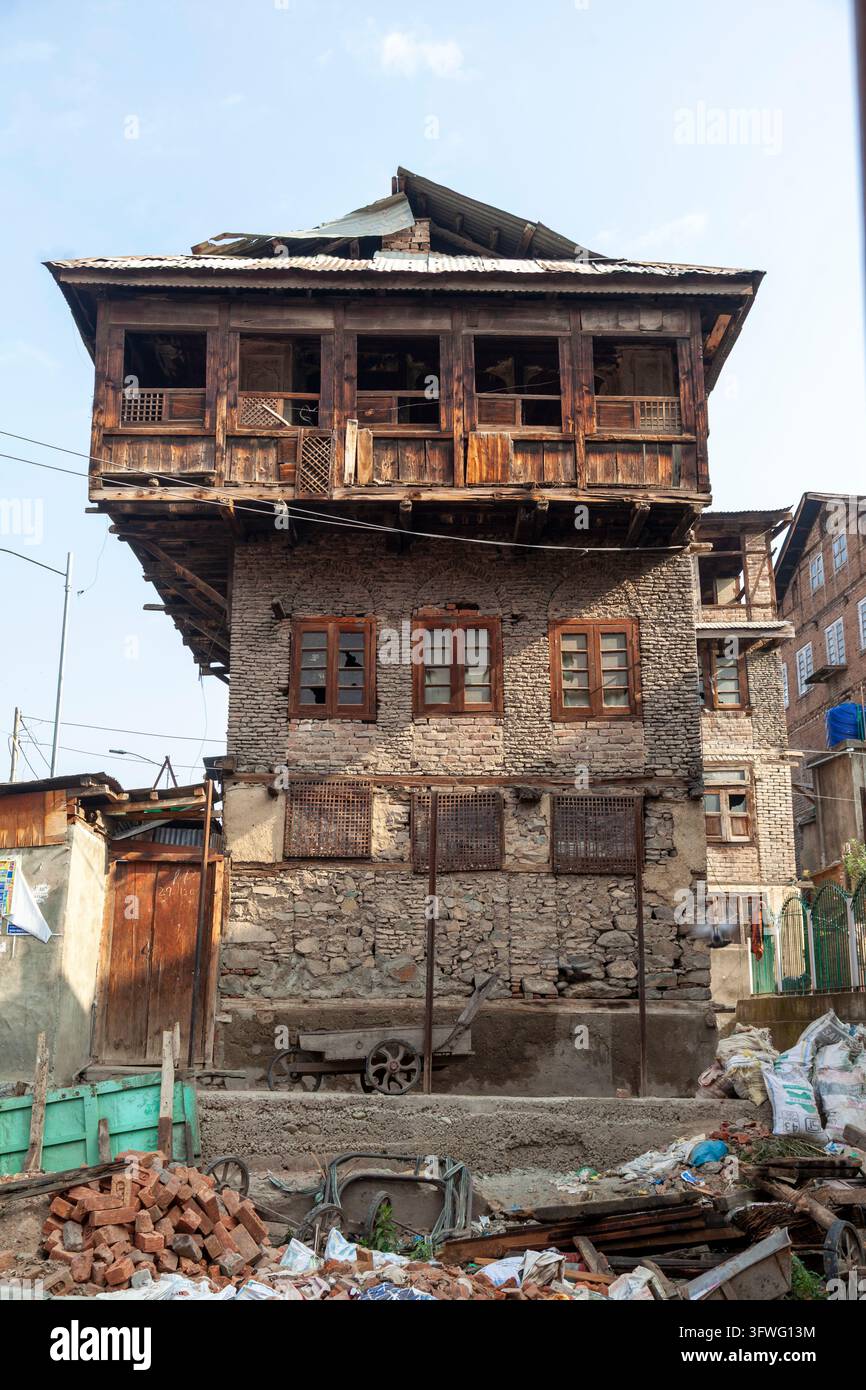 Altes Holz- und Steinhaus, das über einer Abbruchstätte in Jammu und Kashmir, Srinagar, Indien hinausragt Stockfoto