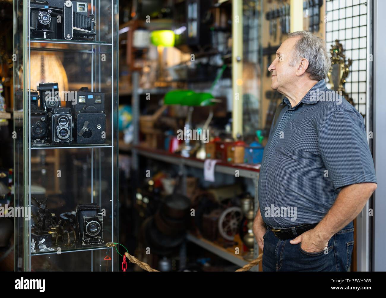 Älterer männlicher Sammler wählt eine alte Filmkamera auf einem Straßenflohmarkt Stockfoto
