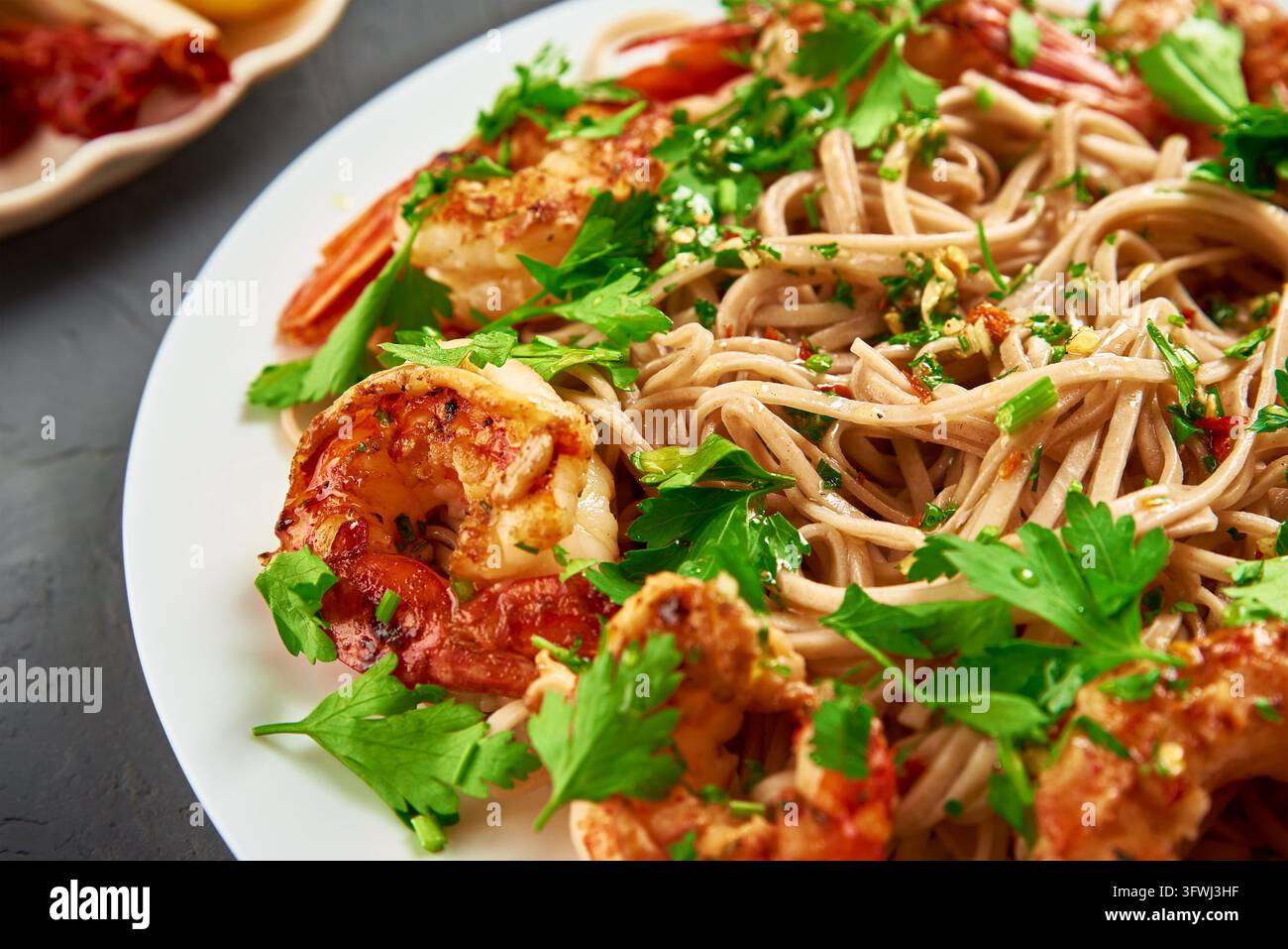 Nudeln mit Garnelen und frischer Petersilie auf weißem Teller, Soba mit Garnelen, asiatische Küche umrühren Stockfoto