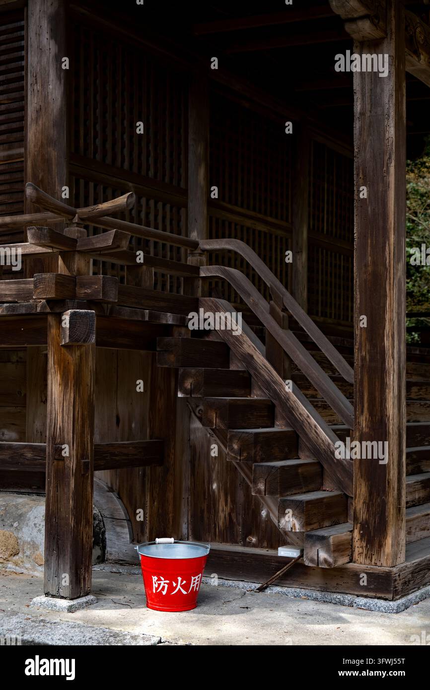 Moderner roter Metall-Feueimer aus Japan gefüllt mit Wasser, bereit, Flammen bei einem Brand im Mii-dera-Tempel in Otsu, Japan, zu löschen. Stockfoto