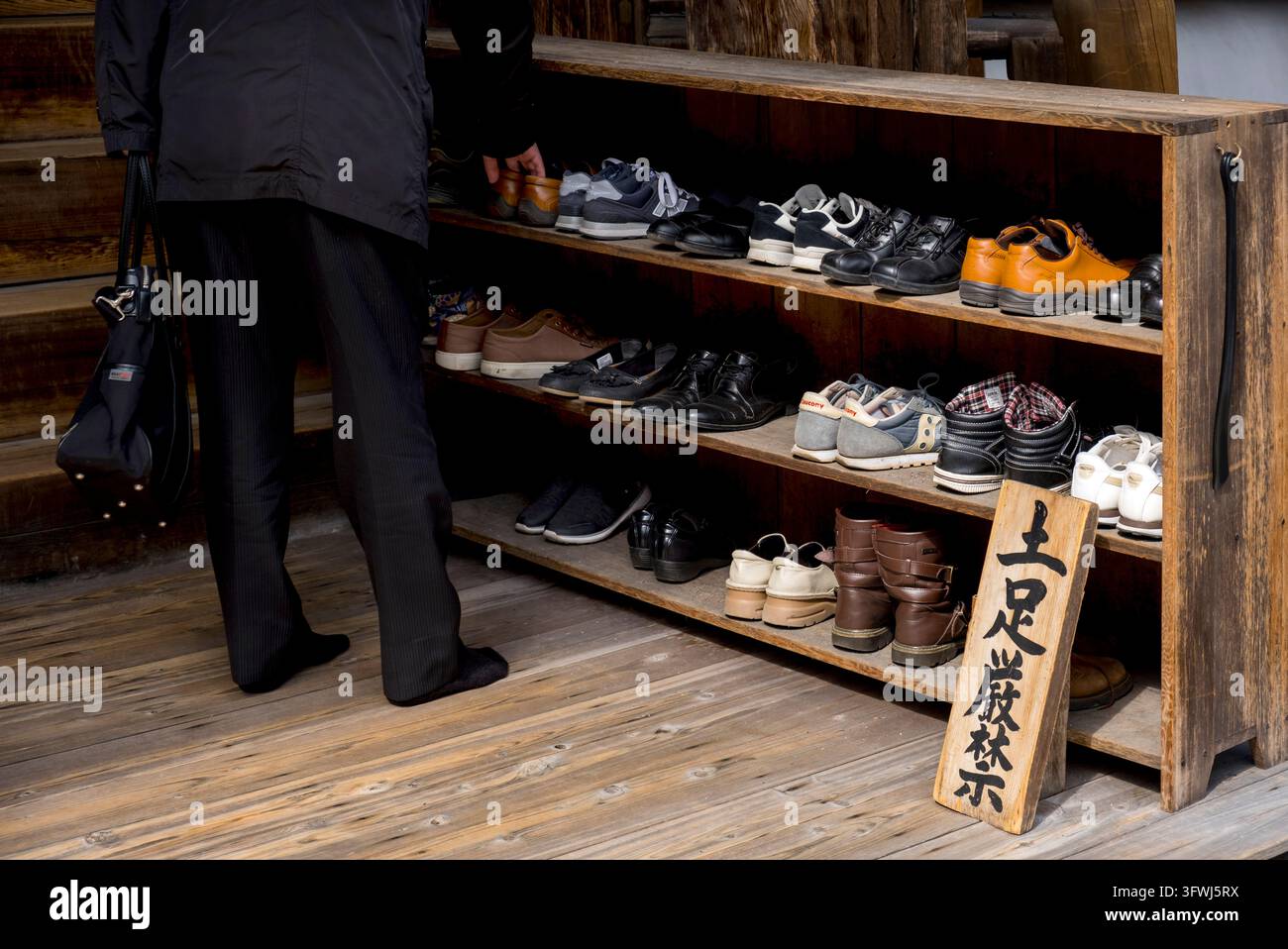Menschen, die Schuhe ausziehen und anziehen, wenn sie einen buddhistischen Tempel betreten und verlassen, der traditionelle Brauch der Schuhentfernung in ganz Japan. Stockfoto