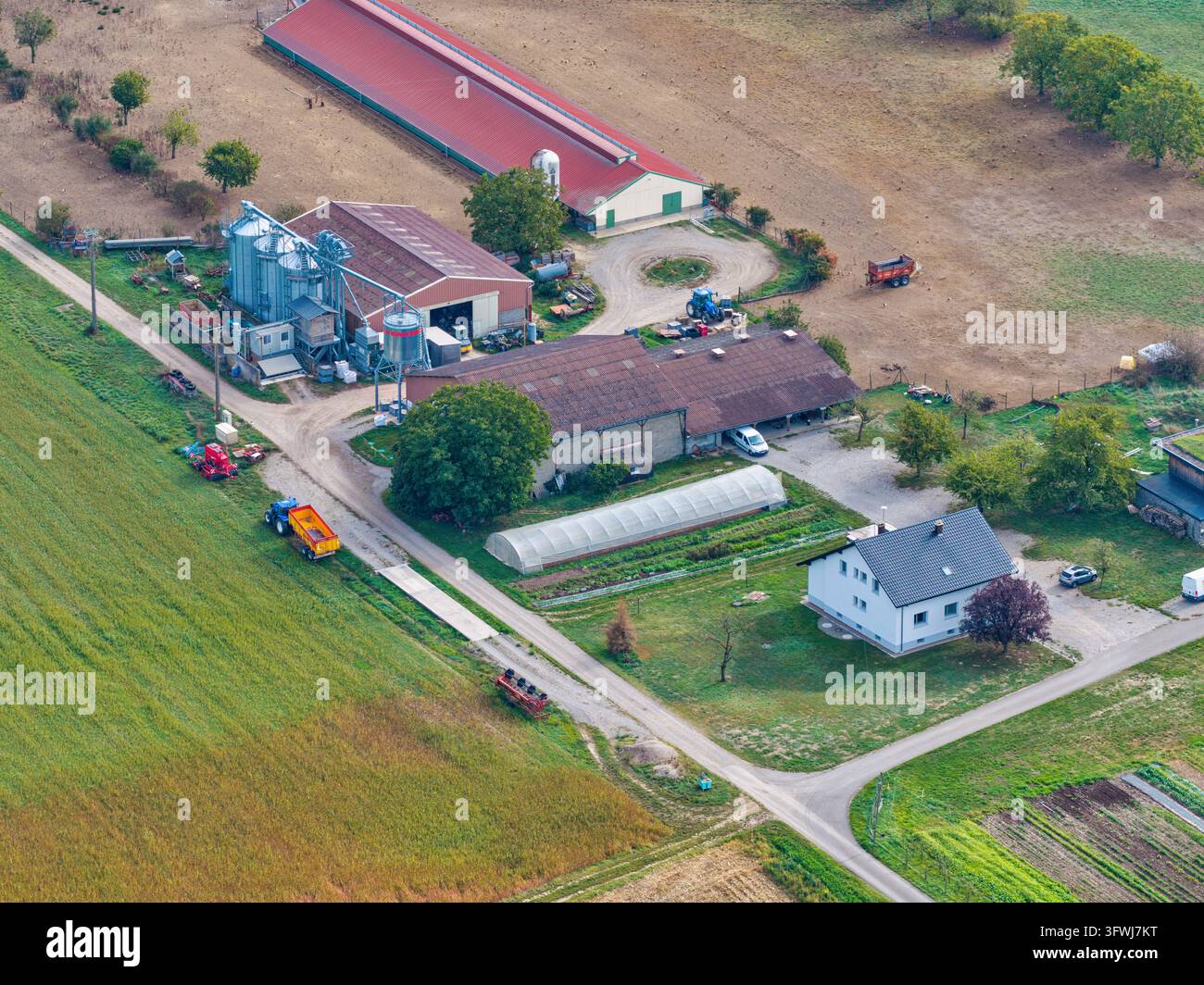 Luftaufnahme einer Farm in Hombourg mit landwirtschaftlichen Gebäuden, Silos, einem Gewächshaus und den umliegenden Feldern in Hombourg, Grand Est, Frankreich. Stockfoto