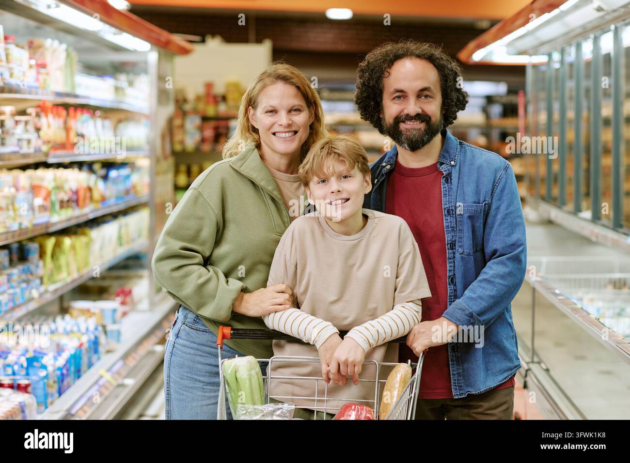 Porträt einer glücklichen Familie mit Kind beim Einkaufen in einem Supermarktgang Stockfoto
