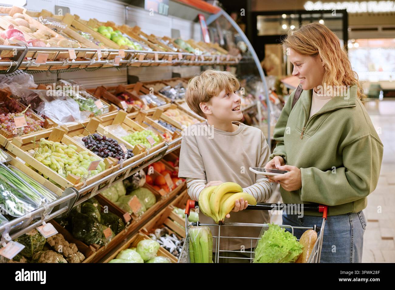 Mutter und Junge wählen frische Lebensmittel im Supermarkt aus Stockfoto
