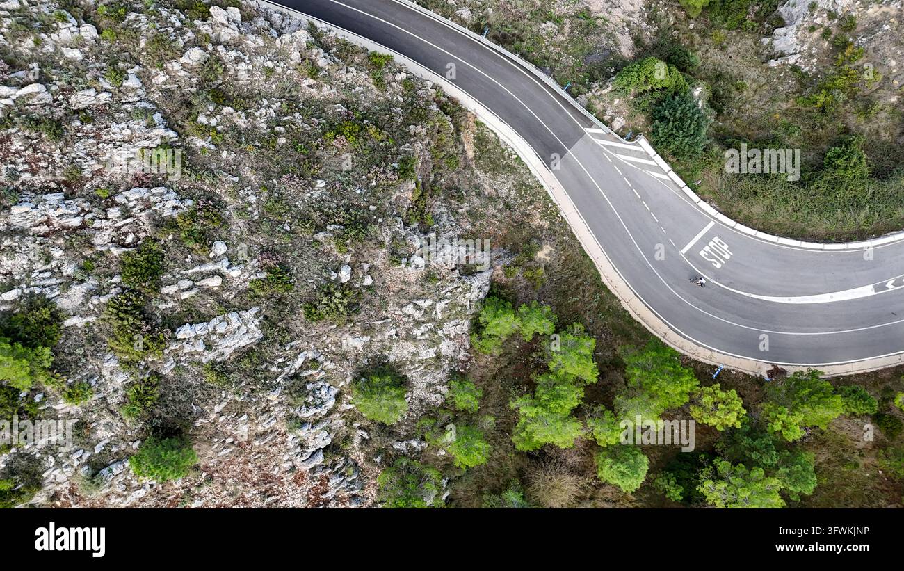 Luftaufnahme der sich windenden Straße am Mirador del Coll de Rates de Parcent, umgeben von felsigem Gelände und Kiefern, Alicante, Valencianische Gemeinschaft, Sp Stockfoto