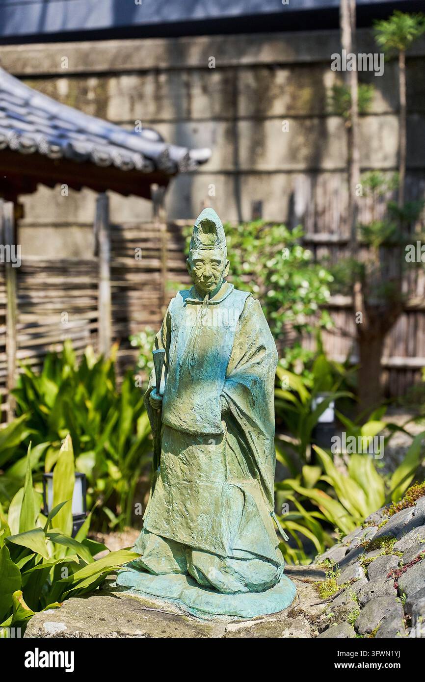 Traditionelle japanische Bronzestatue einer historischen Figur in zeremonieller Kleidung und Kopfschmuck in einem friedlichen Garten in Japan. Stockfoto