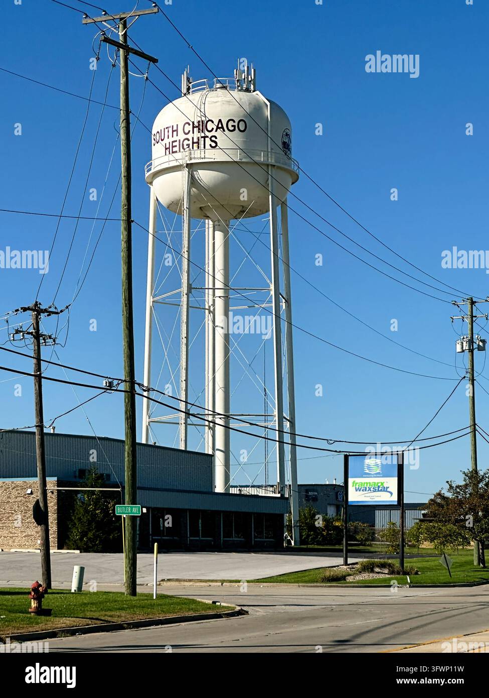 Weißer städtischer Wasserturm vor einem klaren blauen Himmel in South Chicago Heights, Illinois. 11. Oktober 2026 - South Chicago Heights, IL USA - Smartphone-aufgenommenes Stockfoto