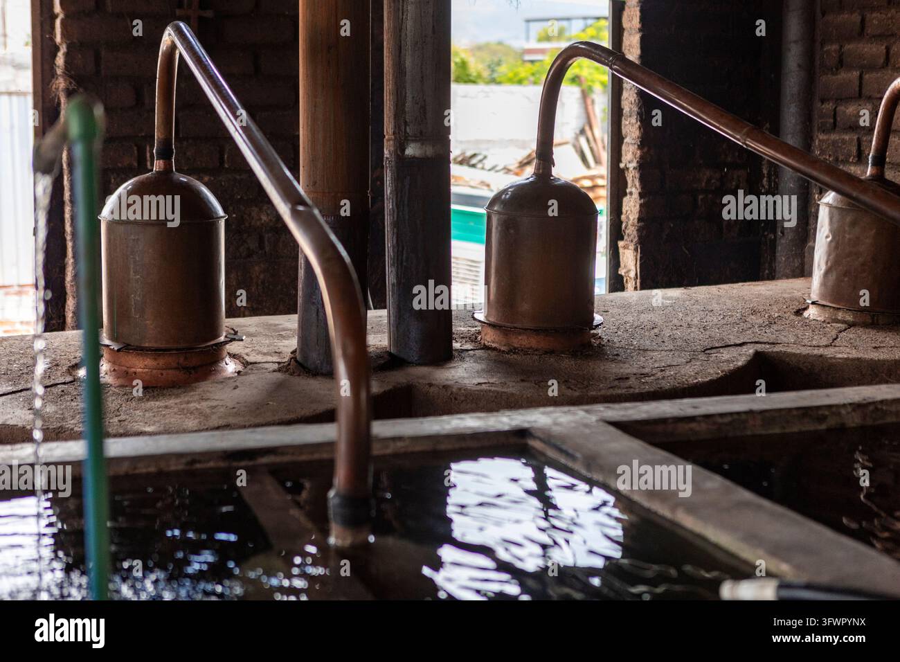 Kupferalembik-Destilliergeräte destillieren Mezcal in einer rustikalen handwerklichen mexikanischen Werkstatt und spiegeln die traditionelle Agaven-Spiritusproduktion und das lokale kulturelle Erbe wider Stockfoto