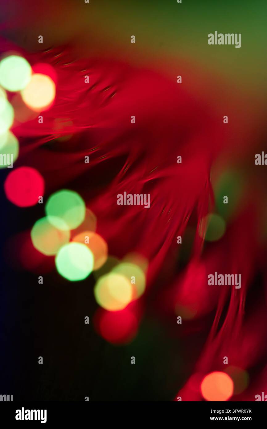 Abstrakte rote Lichtspur, die sich über einen dunklen Hintergrund schlängelt, mit leuchtenden grünen, gelben und orangefarbenen Bokeh-Kreisen, die eine lebendige futuristische Technologie erzeugen Stockfoto