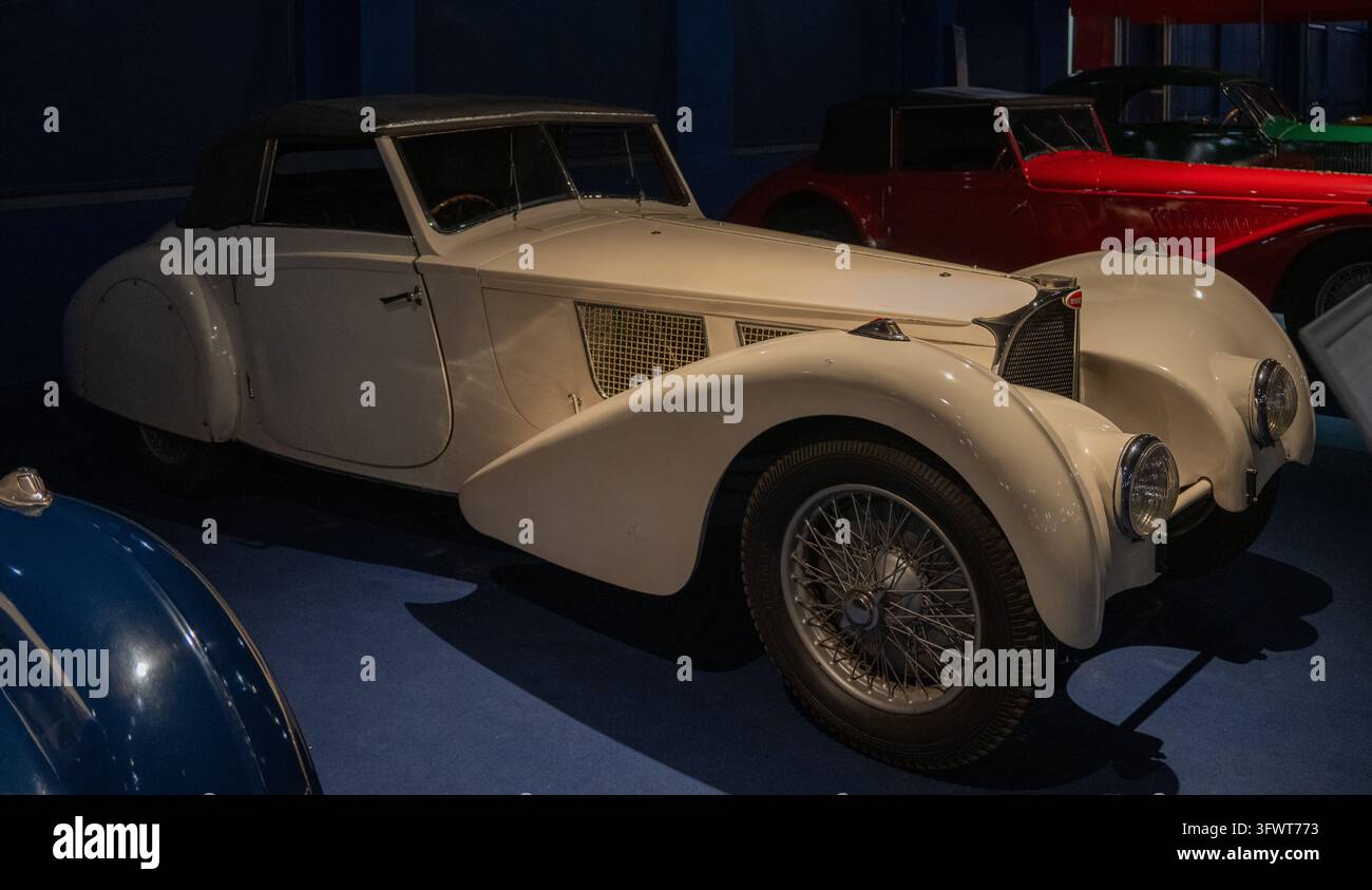 Mulhouse, Frankreich - 24. Jan. 26: Cremefarbenes Bugatti-Cabriolet mit erhöhtem dunklem Dach, geschwungenen Kotflügeln und Drahträdern im Musée National de l'Automobile in M Stockfoto