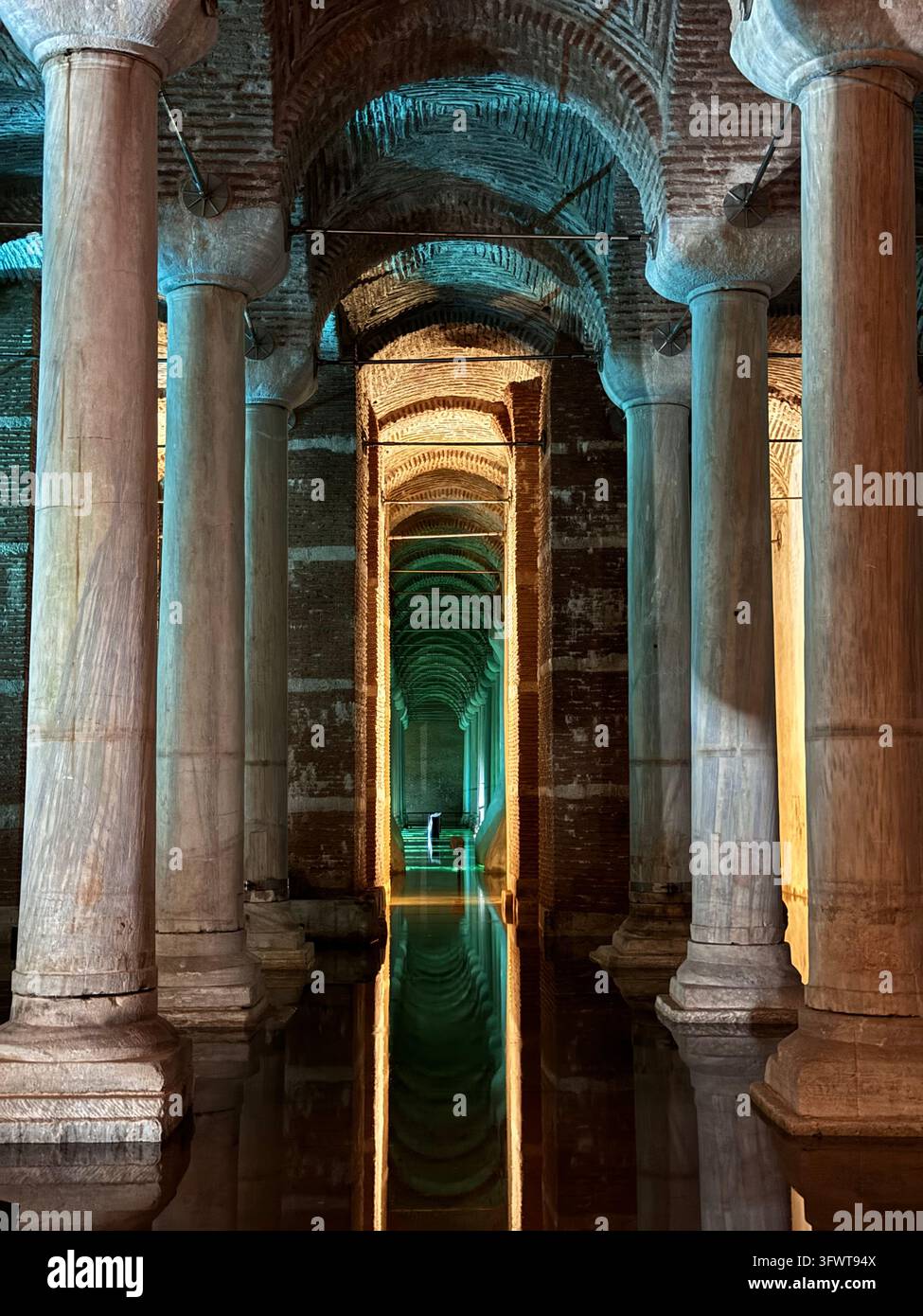 Symmetrischer Korridor aus antiken Säulen mit farbigen Lichtern in der Basilika-Zisterne, Istanbul, Türkei - Smartphone-aufgenommenes Stockfoto