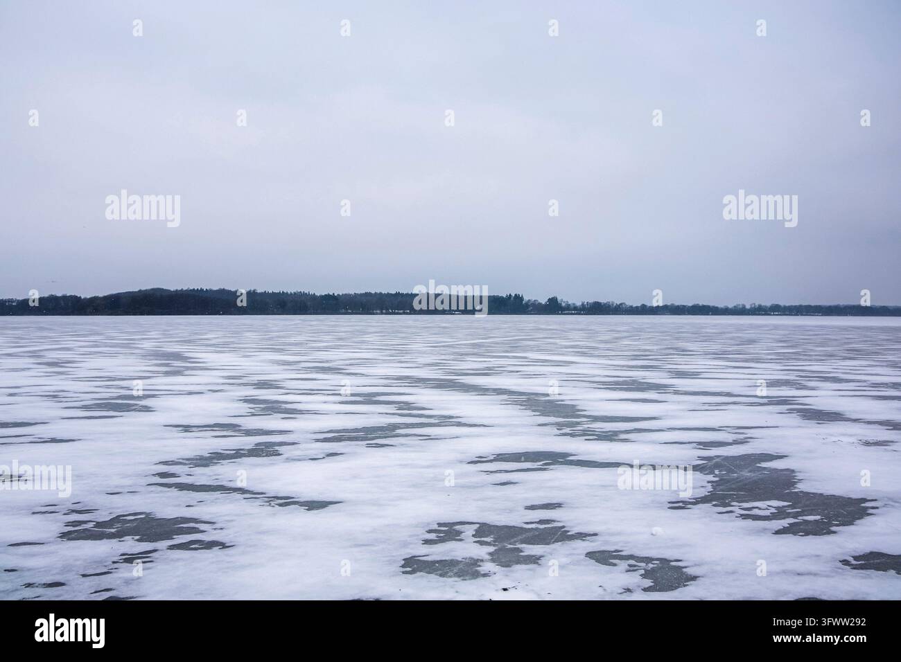 Gefrorene Seenoberfläche bedeckt mit gemustertem Eis und Schnee im Winter Stockfoto