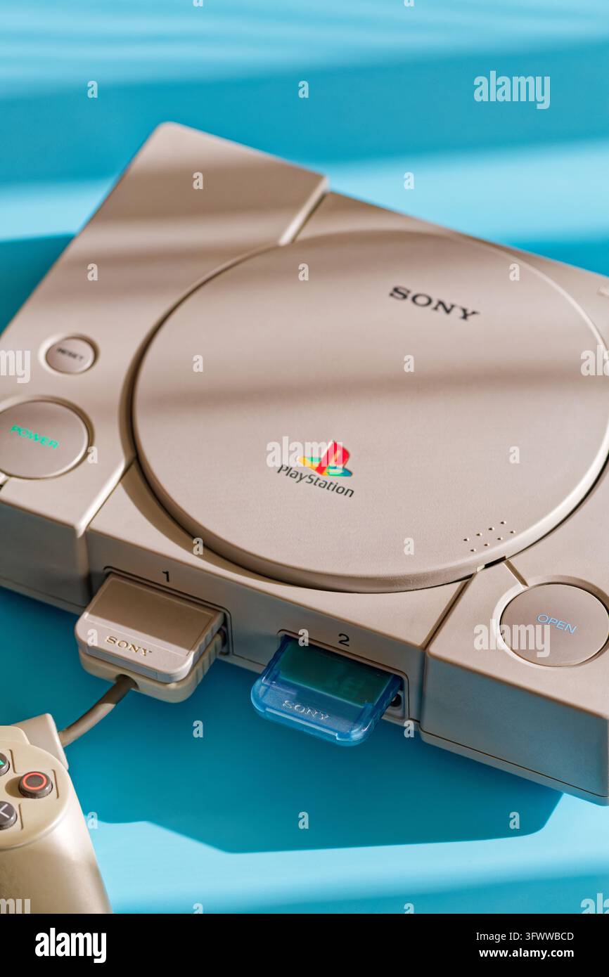 Fukuoka, Japan. 20. Oktober 2026: Nahaufnahme einer originalgrauen Sony PlayStation 1-Konsole auf blauem Hintergrund mit eingelegten Speicherkarten Stockfoto