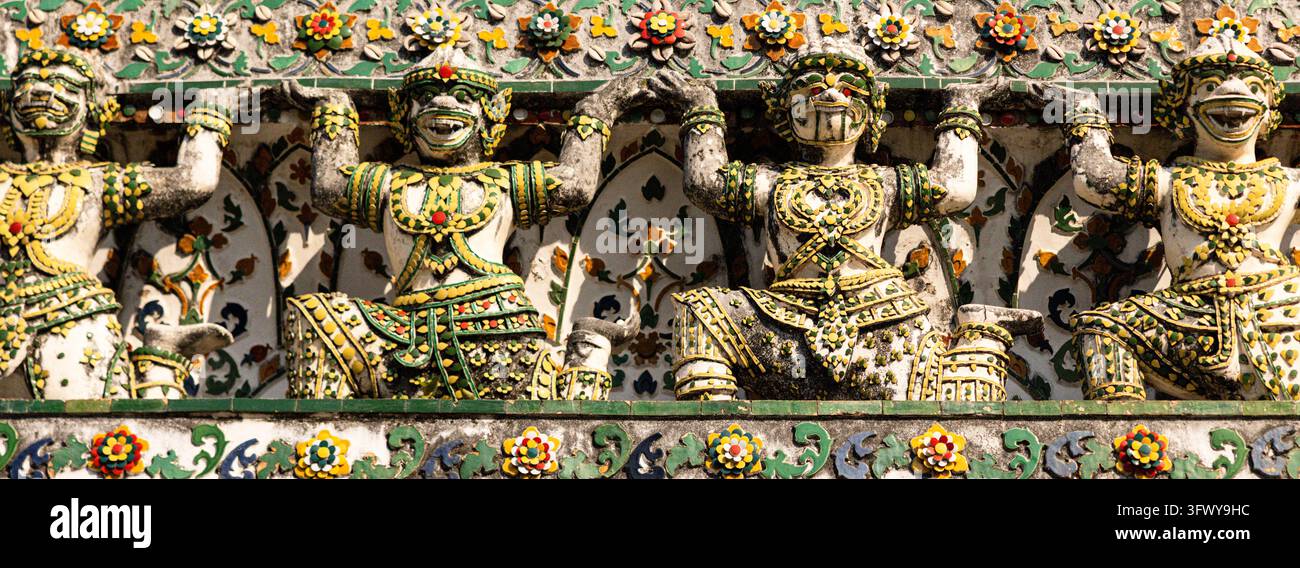Bangkok, Thailand - 1. Februar 2026: Eine Reihe kunstvoller, farbenfroher Wächterstatuen mit Blumenmotiven schmückt eine Tempelmauer. Stockfoto