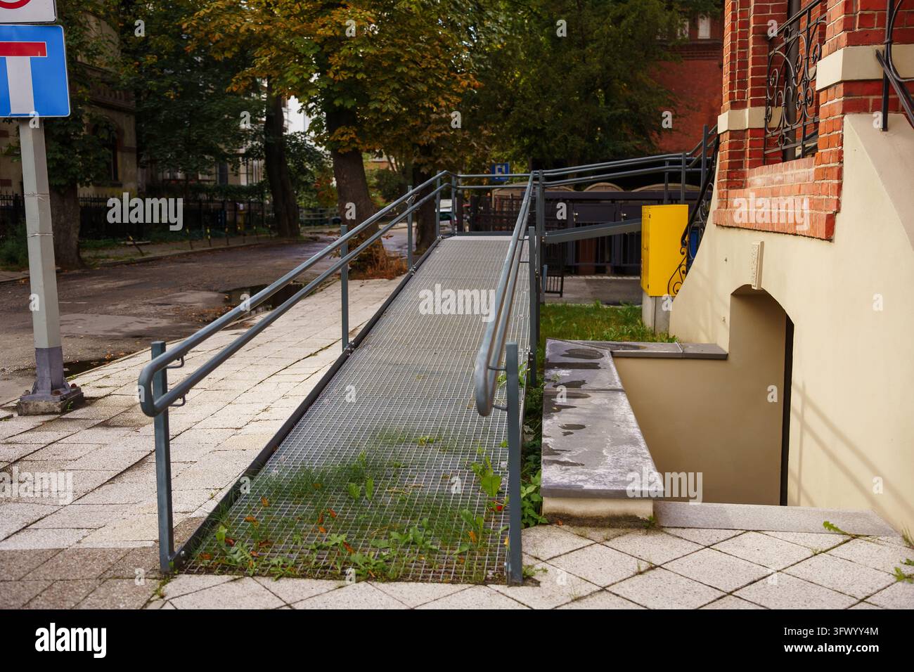 Metall-Rollstuhlrampe mit Sicherheitsgeländern vor einem städtischen Gebäudeeingang, betont Zugänglichkeit, universelles Design und gleiche Mobilität für alle Bürger Stockfoto