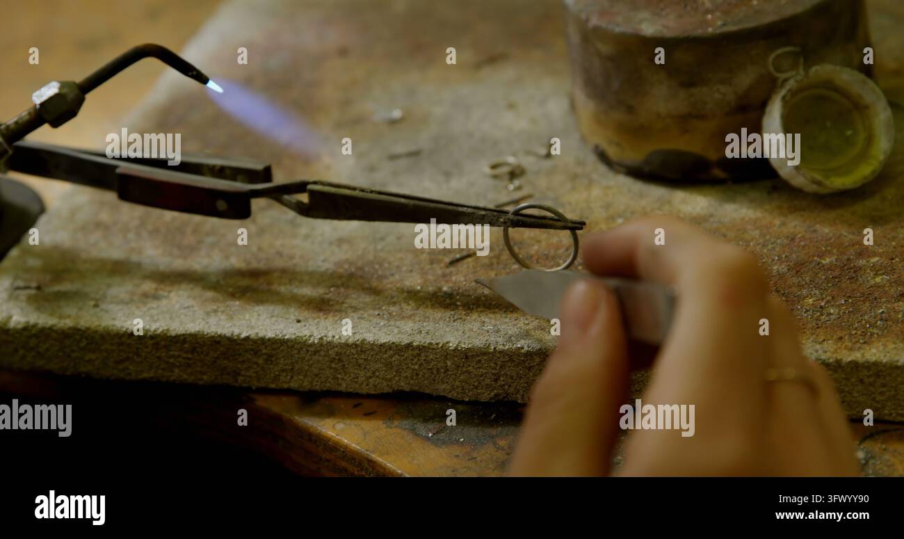 Ein Juwelier arbeitet an einem filigranen Schmuckstück mit einer Taschenlampe und konzentriert sich intensiv auf die feinen Details Stockfoto