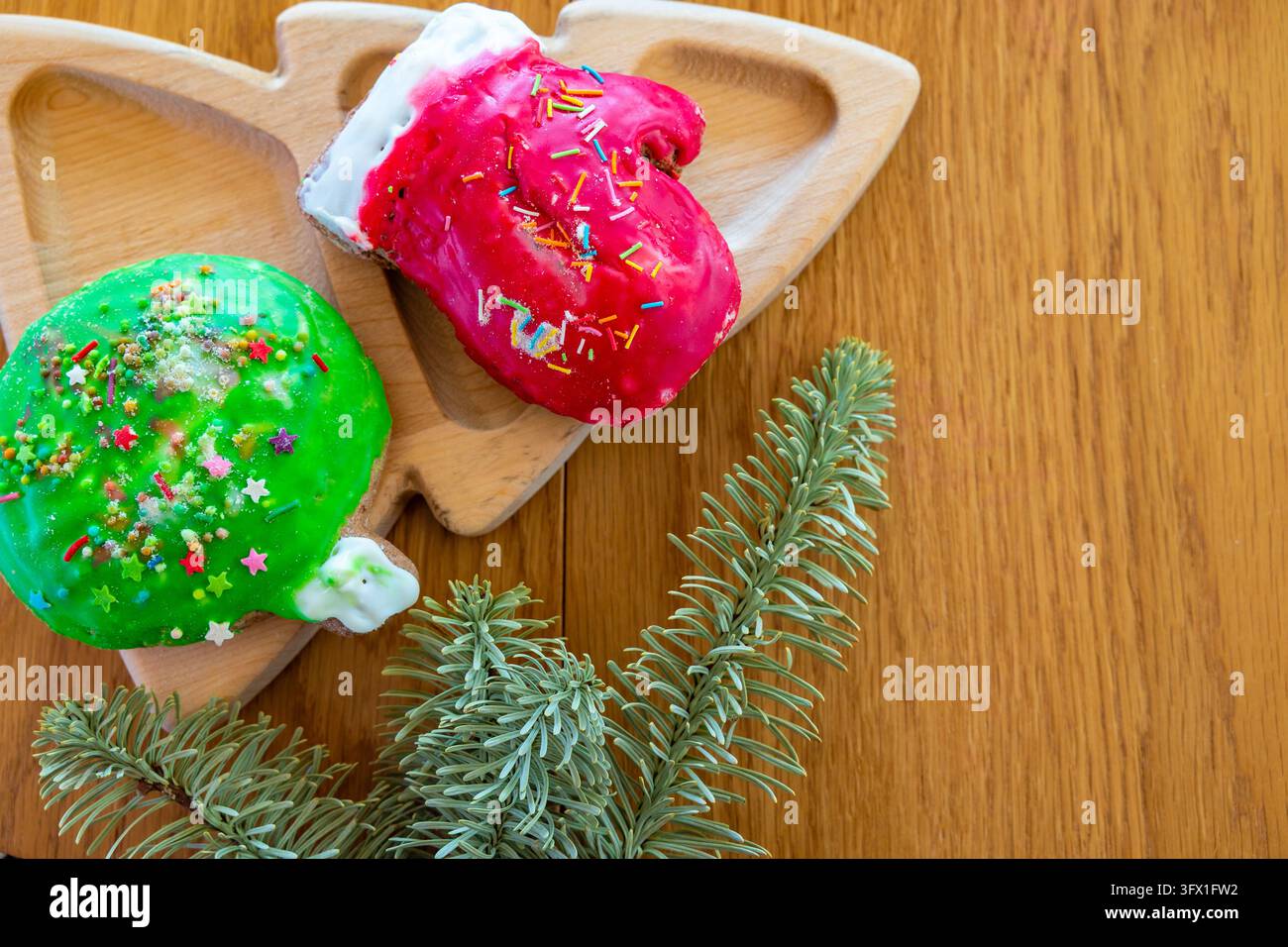 Glänzende Feiertags-Lebkuchen auf einem Holzteller mit Tannenzweigen, nachhaltiges umweltfreundliches Weihnachtsheim-Styling Stockfoto