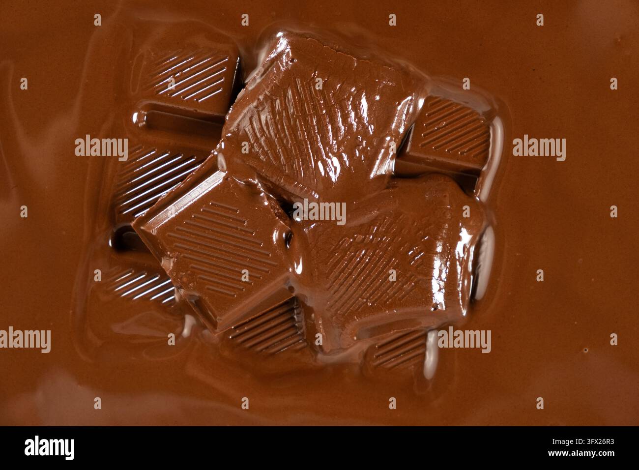 Schmelzende Schokoladenstücke in geschmolzener Schokolade, Nahaufnahme. Stockfoto