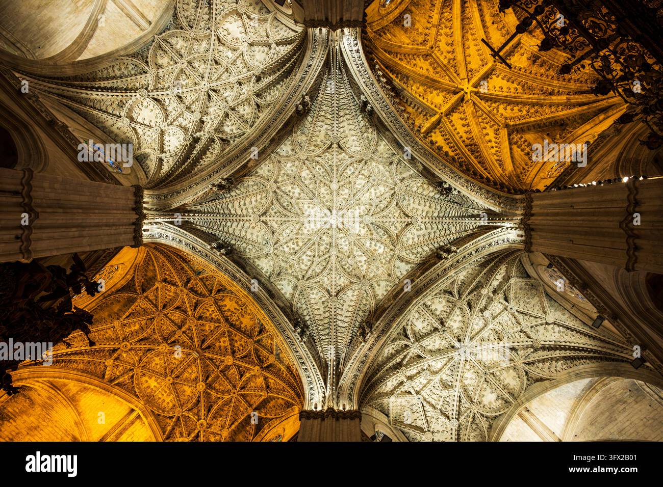 Aufblick zu kunstvollen gotischen Kreuzrippengewölben und geschnitzter Steindekoration im Inneren der Kathedrale von Sevilla, Andalusien, Spanien. Stockfoto