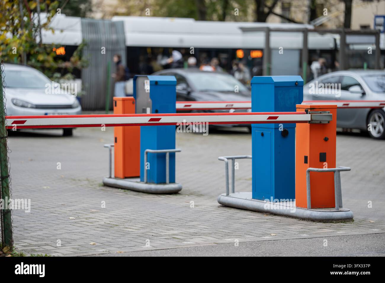 Gesunkene Parkbarrierenarme mit reflektierenden Markierungen überspannen Fahrzeugspuren neben Steuergeräten und veranschaulichen die automatisierte Zugangskontrolle auf einem Parkplatz Stockfoto