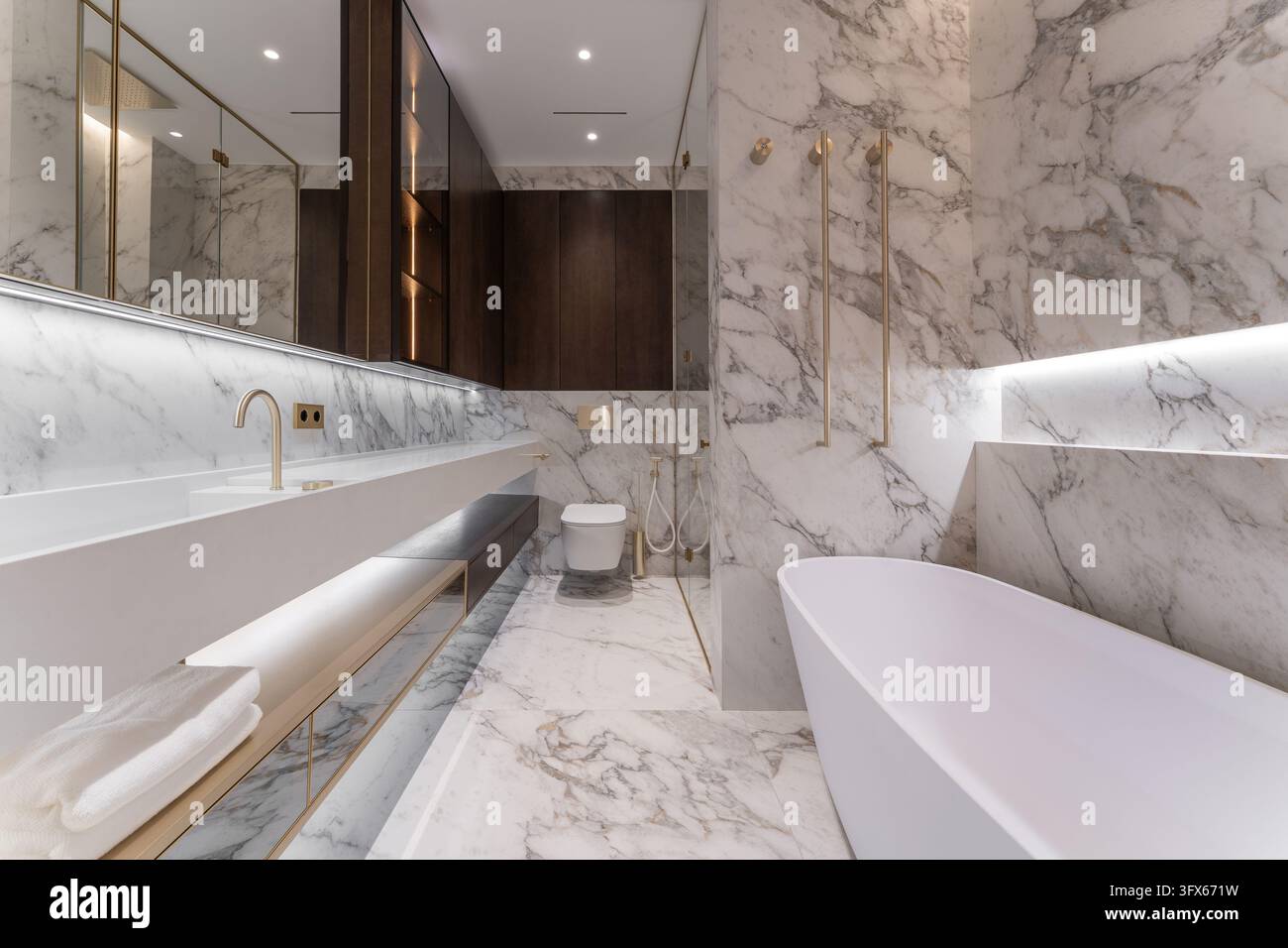 Hochwertiges modernes Badezimmerdesign mit natürlichem weißem Marmor mit grauen Maserungen, schwebender Waschtisch und dunkler Holzschrankfront Stockfoto