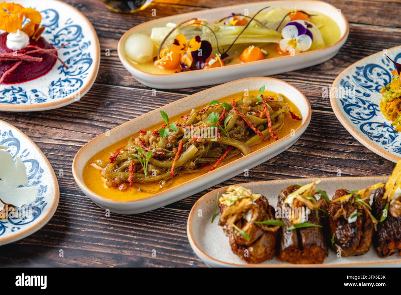 Gourmet-Türkische Meze-Auswahl mit gebratener Aubergine, Gemüse, Dips und essbaren Blüten Stockfoto