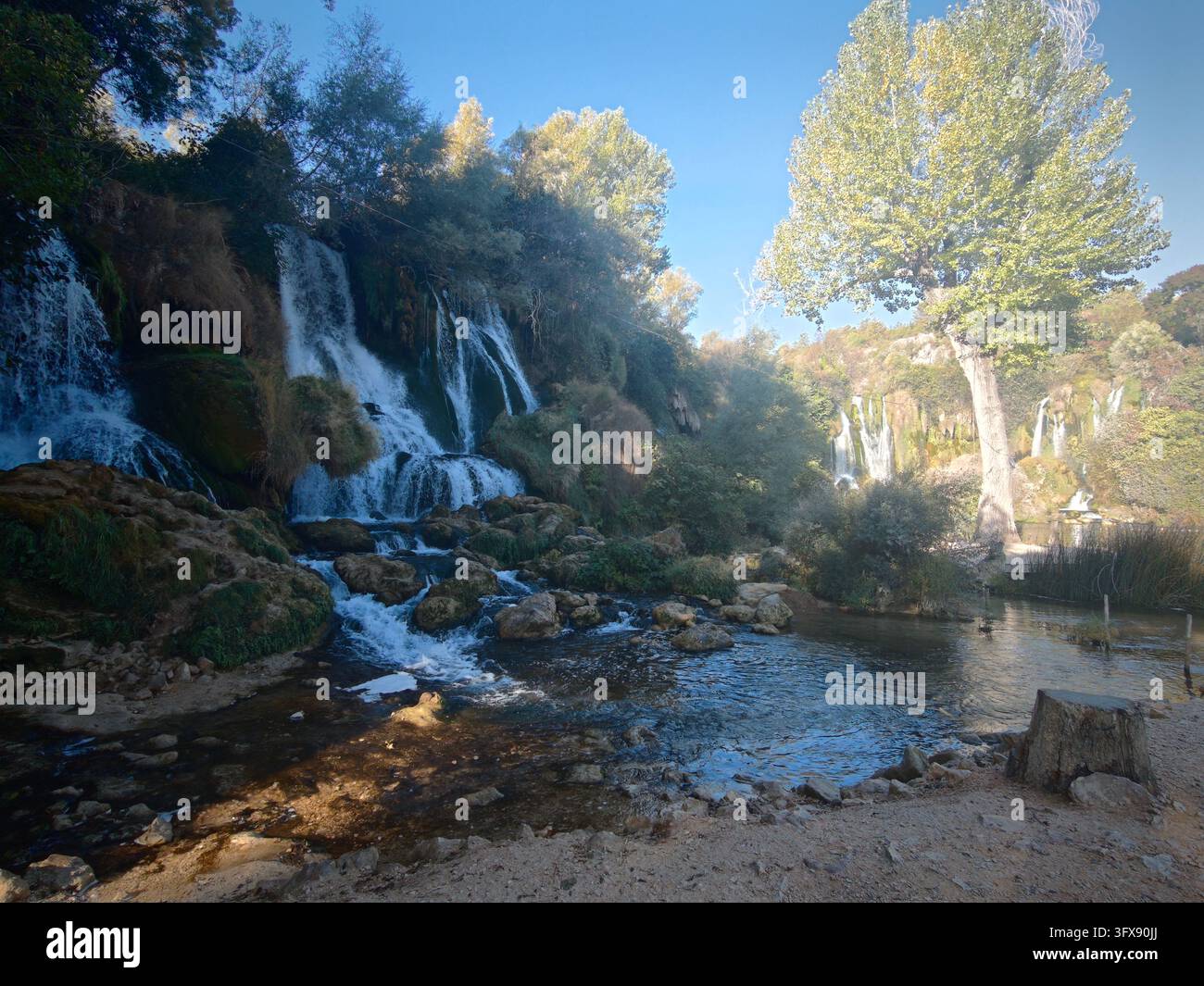 Herbstsonne über den Kravice-Wasserfällen, Bosnien und Herzegowina. Malerische Naturlandschaft mit kaskadierenden Tuffkaskaden und Herbstfarben. - Smartphone-aufgenommenes Stockfoto