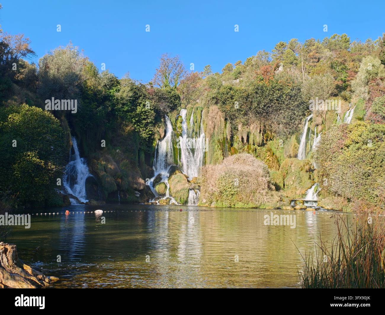 Herbstsonne über den Kravice-Wasserfällen, Bosnien und Herzegowina. Malerische Naturlandschaft mit kaskadierenden Tuffkaskaden und Herbstfarben. - Smartphone-aufgenommenes Stockfoto
