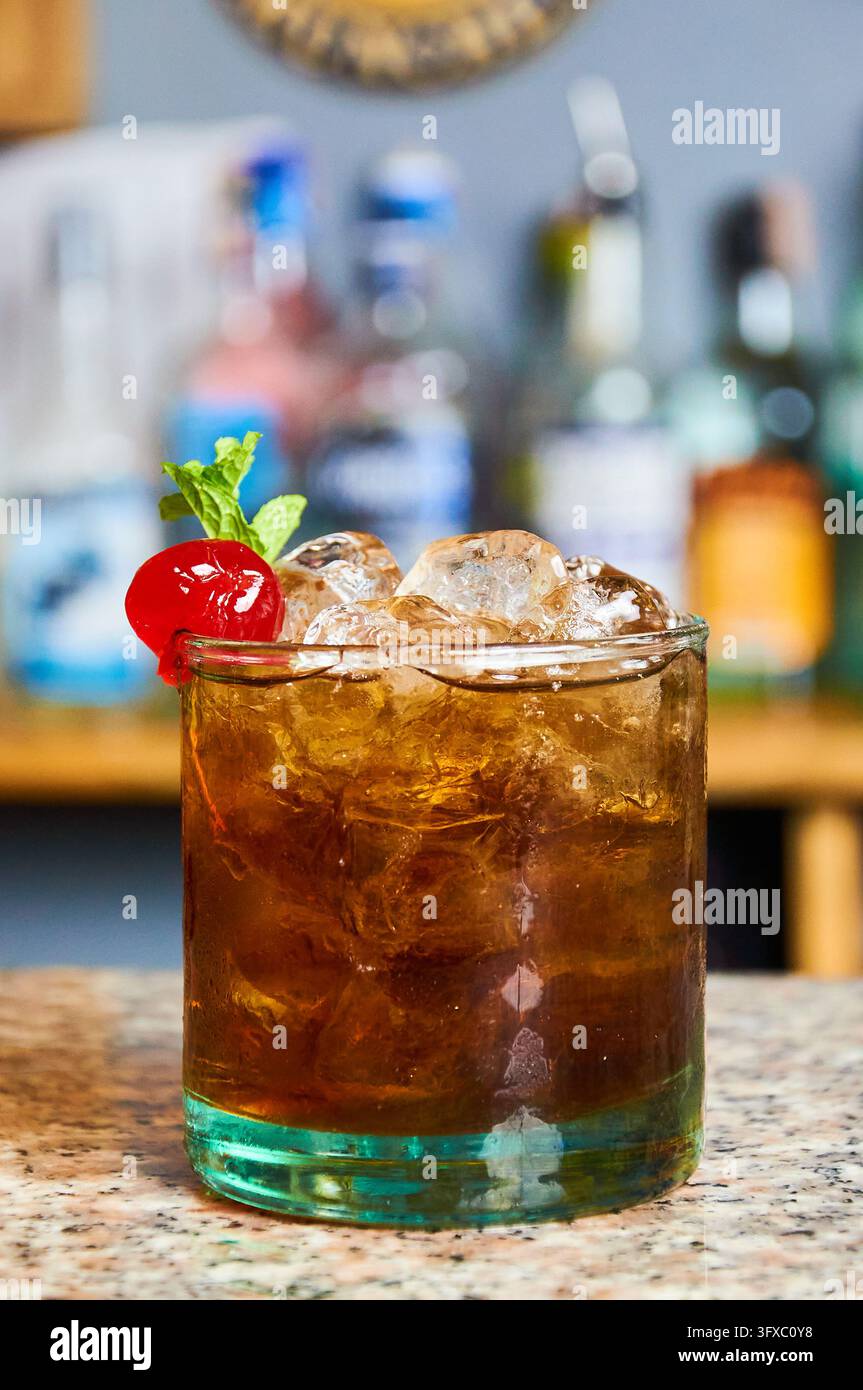 Cuba-libre-Rum-Cola-Cocktail mit Eis und einer Kirsche in einem Rocks-Glas. Stockfoto