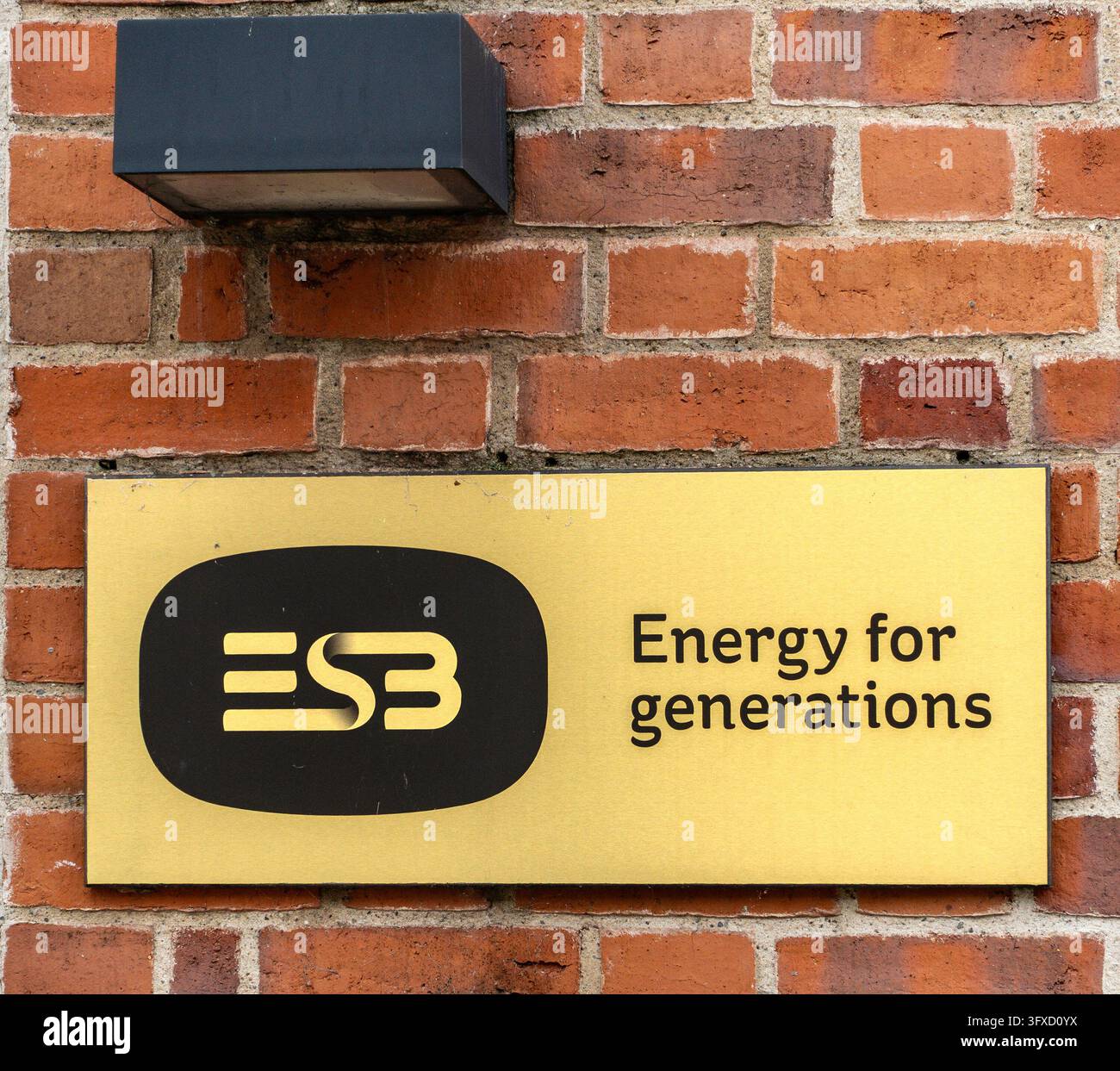 ESB-Plakette mit dem Slogan "Energie für Generationen" montiert an einer roten Backsteinmauer im Freien unter einer Straßenlaterne in Dublin. Stockfoto