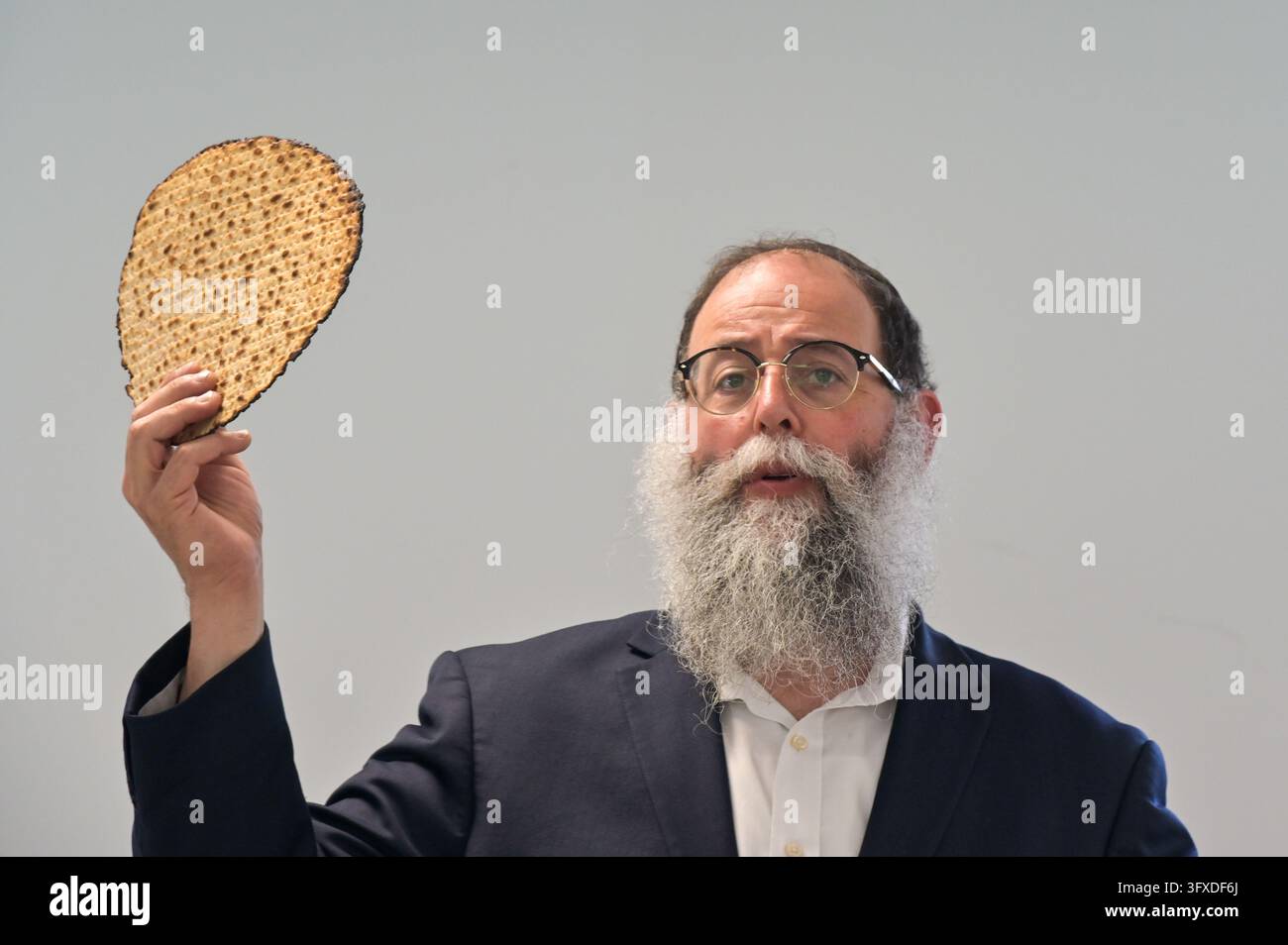 BRISBANE - 18. APR 2024: Rabbiner segnet Matzah, ungesäuertes Fladenbrot beim Passah-Seder, einem Festmahl, das das Lesen der Haggadah, des Buches Exodus über Go beinhaltet Stockfoto