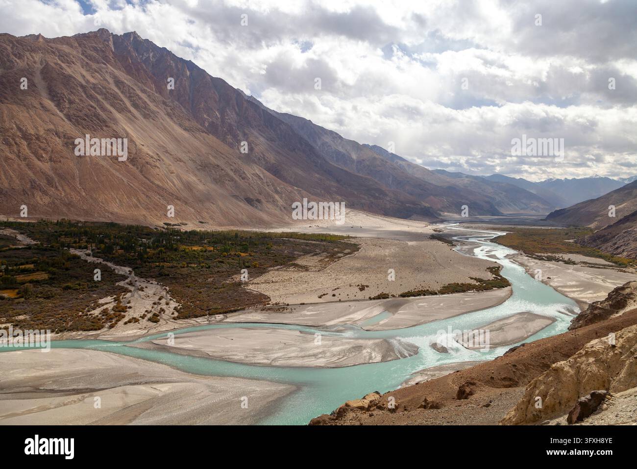 Türkis gefälselter Fluss windet sich durch ein weites Tal unter einem bewölkten Himmel, Ladakh, Turtuk, Indien Stockfoto