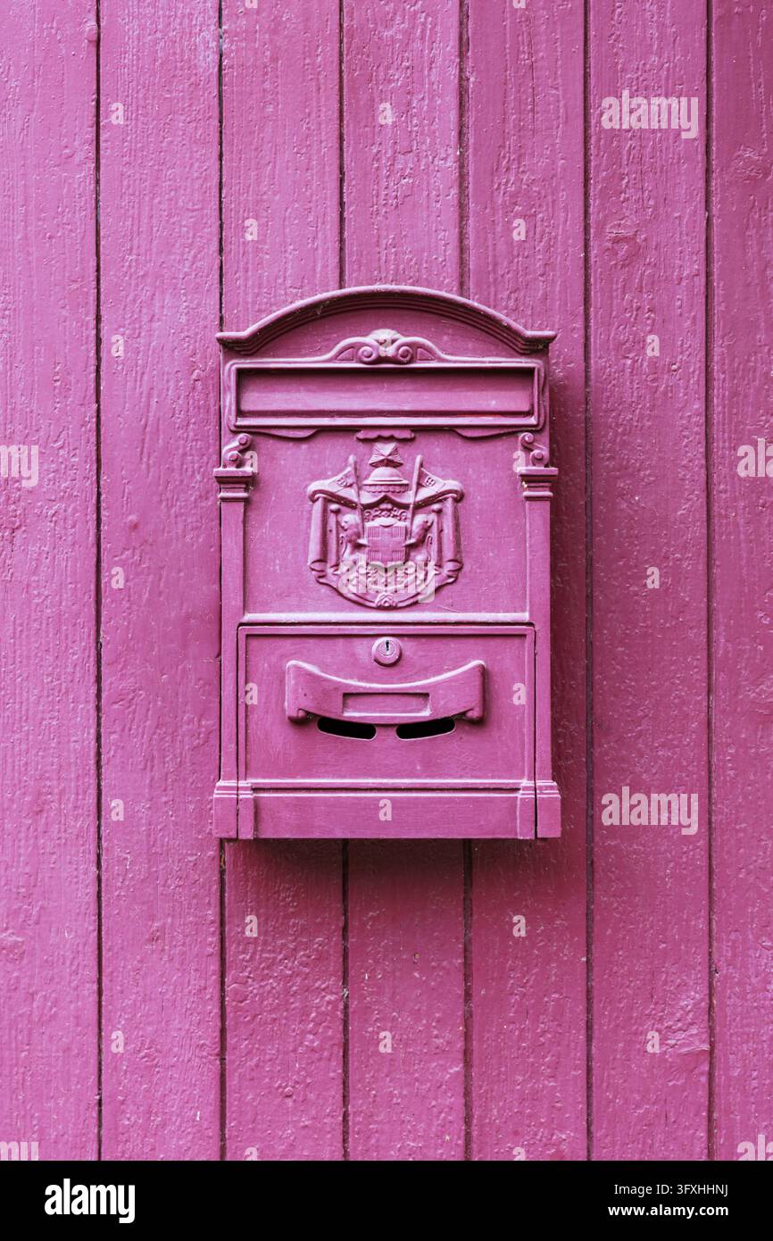 Ein metallener Briefkasten, rot gestrichen, an der roten Tür eines Hauses Stockfoto