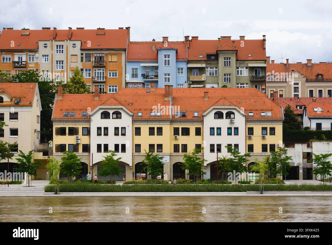 Symmetrische Fassade historischer und moderner Wohnungen mit roten Dächern entlang des renovierten Lent-Ufers an der Drau in Maribor, Slowenien. Stockfoto