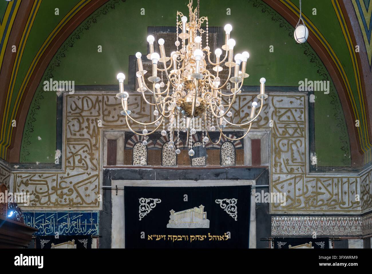 Hebron, Palästinensische Gebiete – 23. Jan. 2026: Ein Kronleuchter erhellt das kunstvoll verzierte Innere der Höhle der Patriarchen, mit arabischer Kalligrafie an den Wänden a Stockfoto