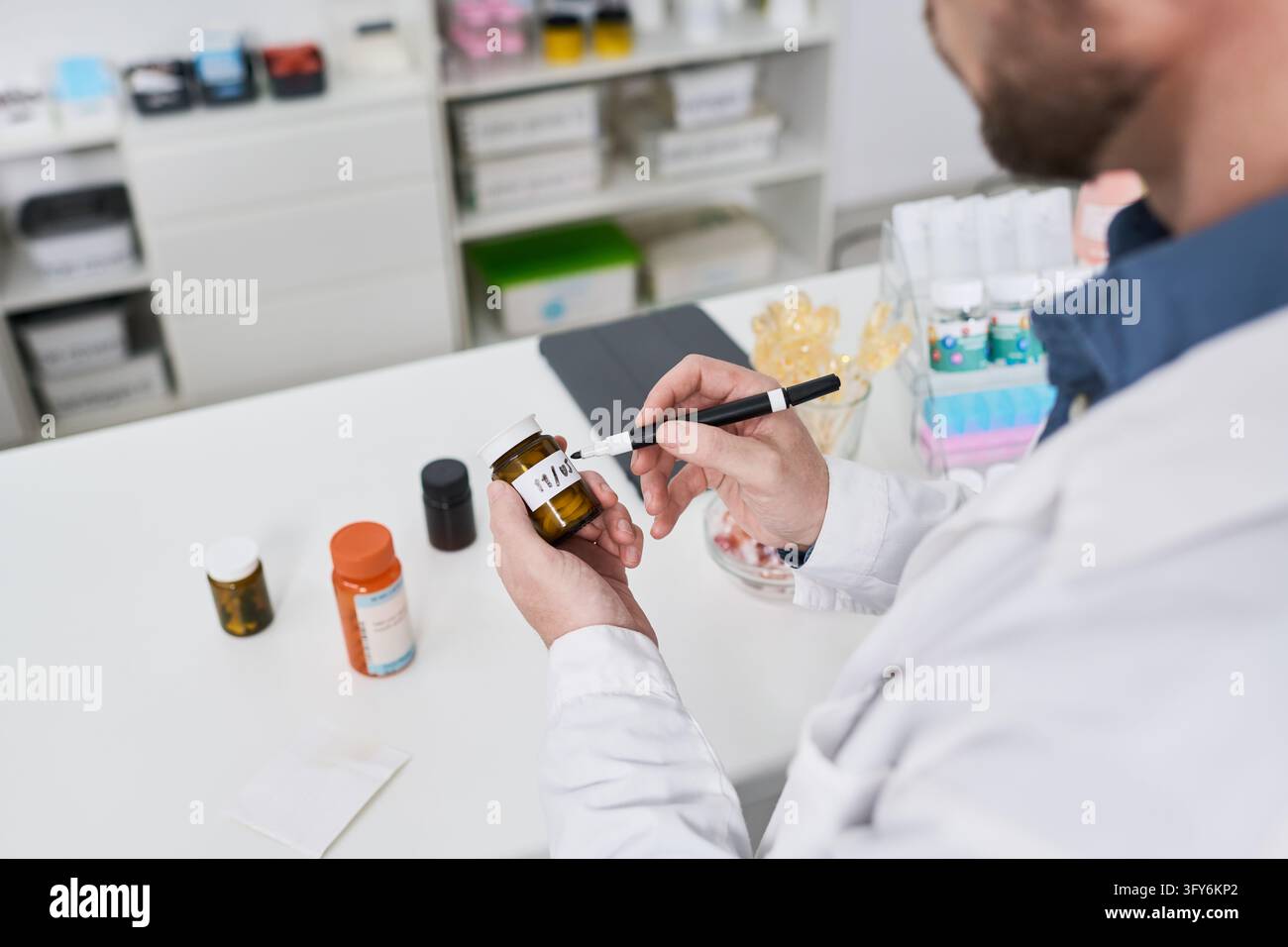 Apotheker etikettiert ein Rezeptfläschchen am Apothekenschalter Stockfoto