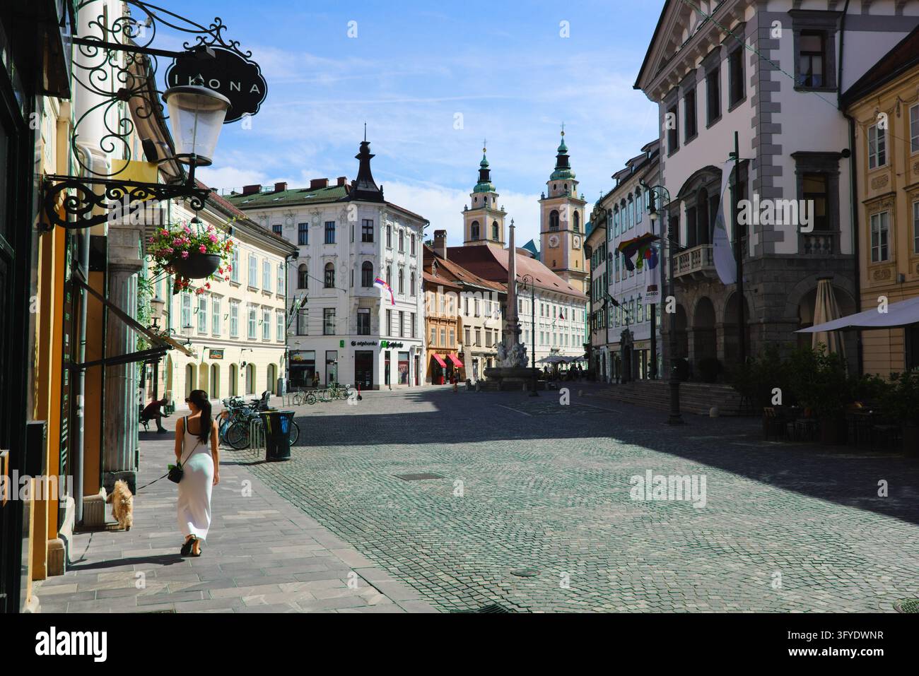 Weitläufiger Blick auf den Stadtplatz mit der Robba-Fontäne und den Türmen der St.-Nikolaus-Kathedrale unter einem blauen Himmel in Ljubljana, Slowenien. Stockfoto