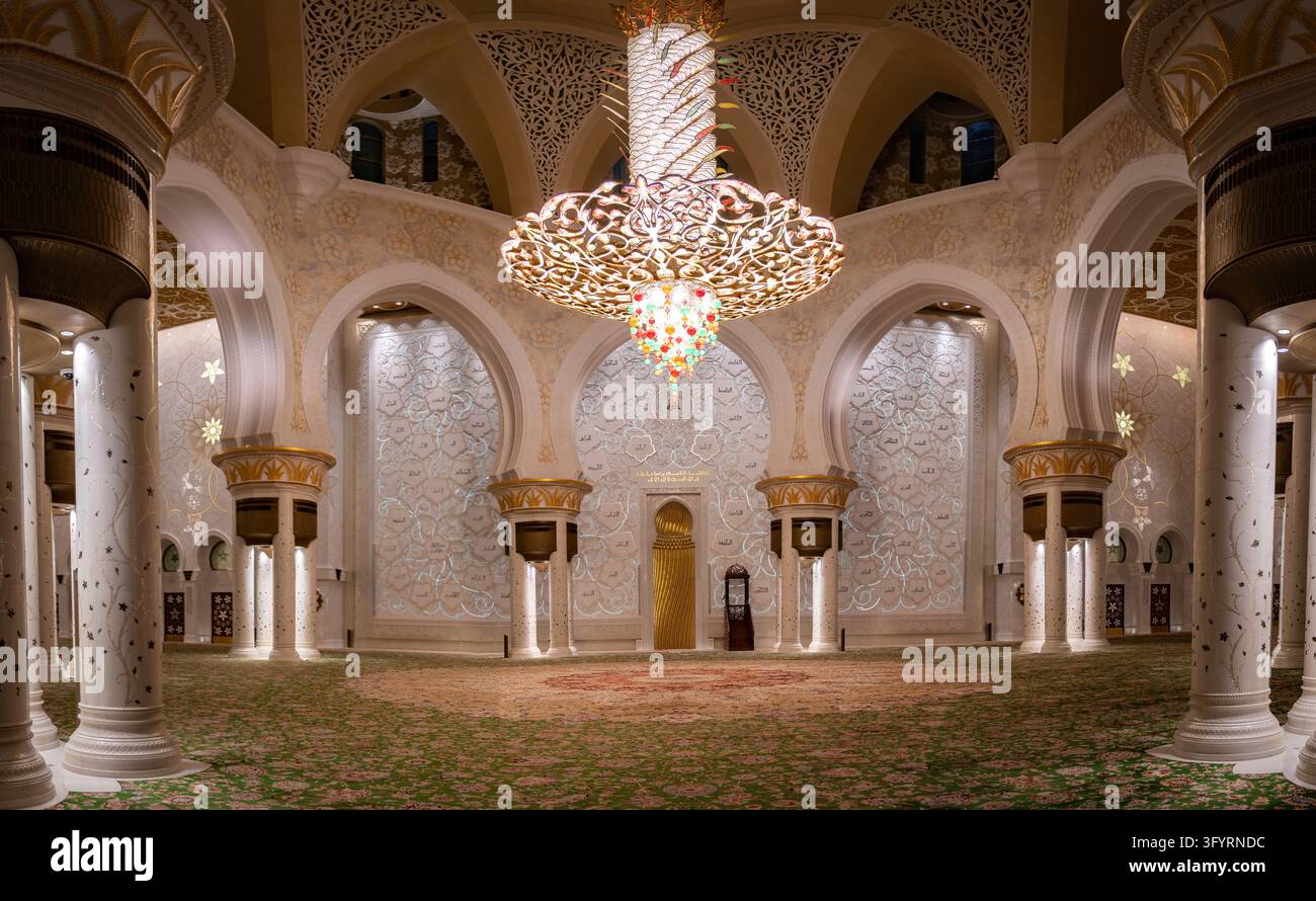 Abu Dhabi, VAE - 18. Februar 2022: Riesiger goldener und kristallener Kronleuchter, der über dem Teppichboden des Hauptgebetssaals der Scheich-Zayed-Großmoschee hängt, sur Stockfoto