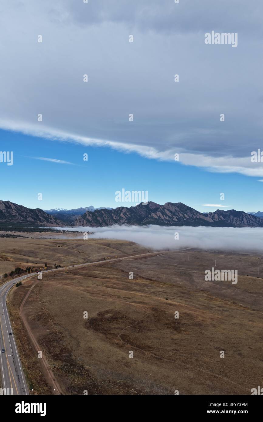 Luftbild der Rocky Mountains mit einer Schicht tief hängenden Nebels über den Ebenen und einer sich durch die Landschaft schlängelnden Autobahn in Superior, Colorado Stockfoto